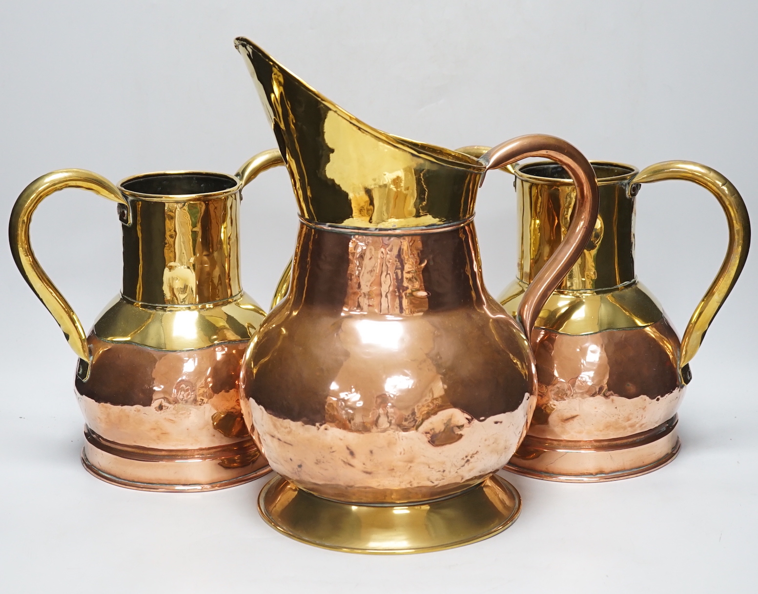 A pair late 19th century copper and brass twin handled vases and a similar jug, the largest 35cm high (3)